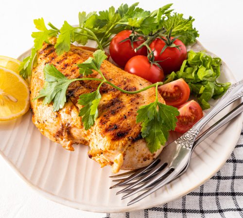large textured ceramic plate with grilled chicken fillet with fresh vegetables.improve the taste.
